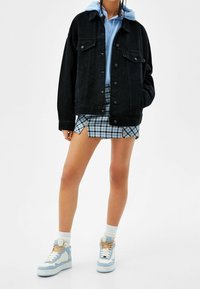 Svart denimjacka med framfickor, bärs över en ljusblå hoodie och en rutiga minikjol. Matchas med ljusblå sneakers.