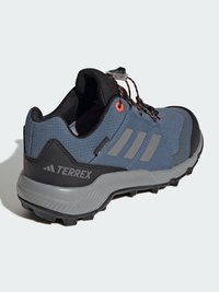 Chaussure de randonnée légère bleue avec des accents gris, supérieure en maille texturée et semelle en caoutchouc noire présentant des crampons profonds pour une bonne traction. Détails réfléchissants inclus.