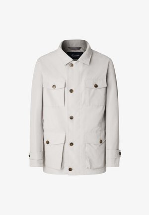 Giacca beige chiaro realizzata in un misto cotone. Caratterizzata da un collo a camicia, sei tasche frontali e grandi bottoni marroni. Design a taglio dritto.