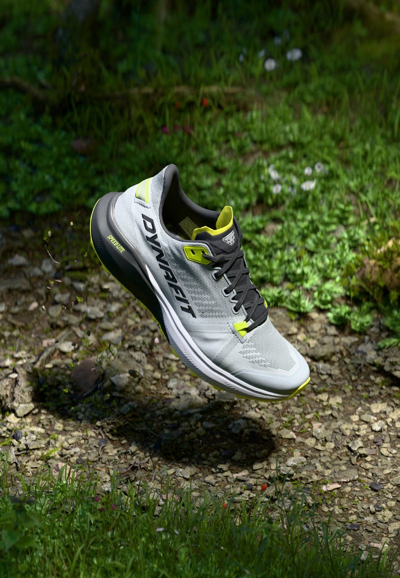 Chaussure de course avec une tige en maille grise, des lacets noirs et des accents jaune fluo. Design léger avec une semelle rembourrée pour un soutien optimal.