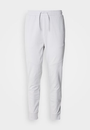 Hvite joggebukser laget av mykt stoff, med elastisk midjebånd og snøring, to sidelommer og ribbestrikkede mansjetter ved anklene.