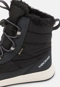 Čierne zateplené čižmy s vodoodolnou značkou Gore-Tex, umelou kožušinou vo vnútri, polstrovaným golierom a textúrovanou podrážkou. Obsahujú elastické šnúrky a logo.