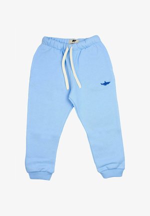 Pantaloni della tuta per bambino in azzurro chiaro con vita elastica, cordoncini bianchi, polsini a coste e piccola ricamatura di uno squalo blu sulla gamba destra.