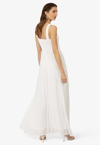 Witte maxijurk met een aansluitend, geraffineerd lijfje, brede banden en een vloeiende rok. Gemaakt van lichte stof, heeft een losse, elegante silhouet.