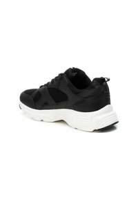 Zapatilla deportiva negra con parte superior de malla y sintético, suela blanca, diseño de cordones, cuello acolchado y acentos texturizados en el lateral.