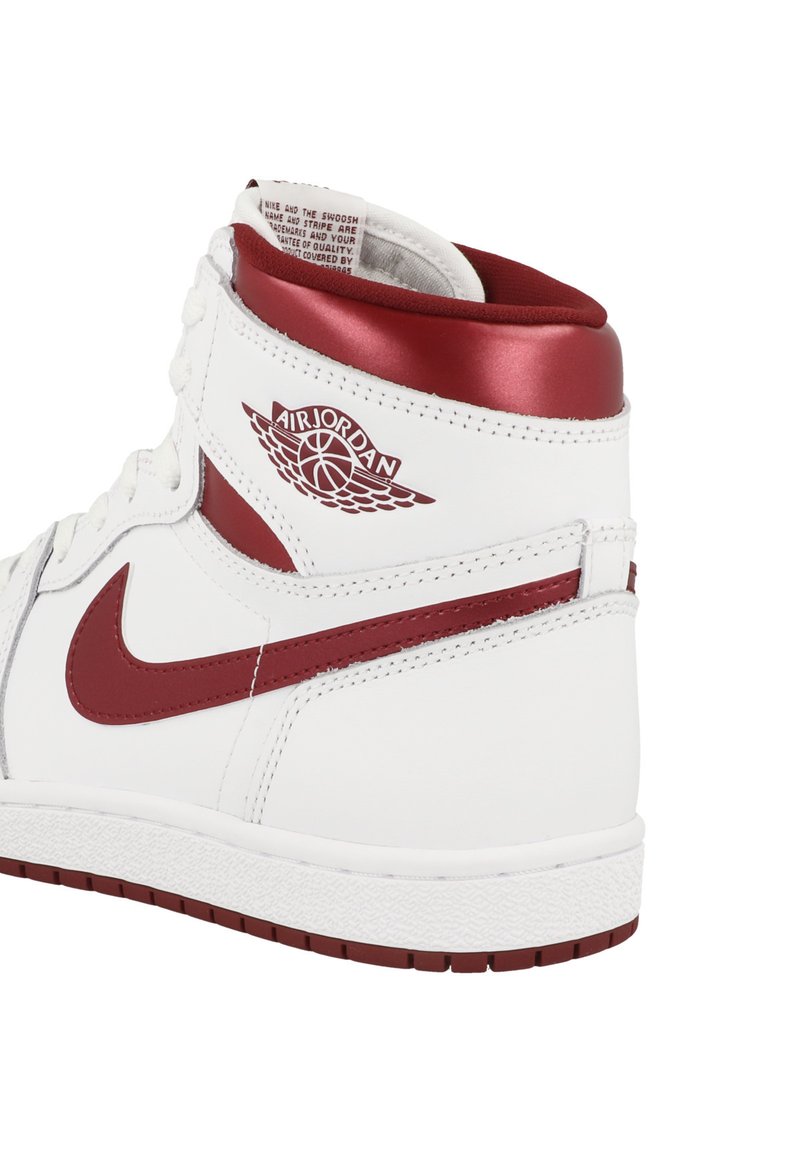 Zapatilla alta Air Jordan blanca y marrón mostrando vista lateral con el swoosh de Nike y el logo de Air Jordan en forma de ala.