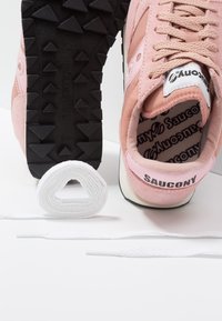 Baskets roses avec dessus en suède et mesh, semelle en caoutchouc noire à picots, et lacets blancs. Logo sur la languette et le talon.