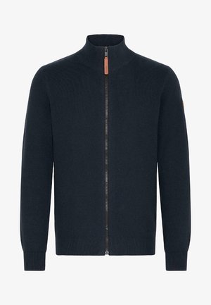 Moška zapenjača v temno modri barvi. Ima visok ovratnik, rebraste manšete in rob. Narejena je iz mehkega pletenega materiala z usnjenim dodatkom na zadrgi.