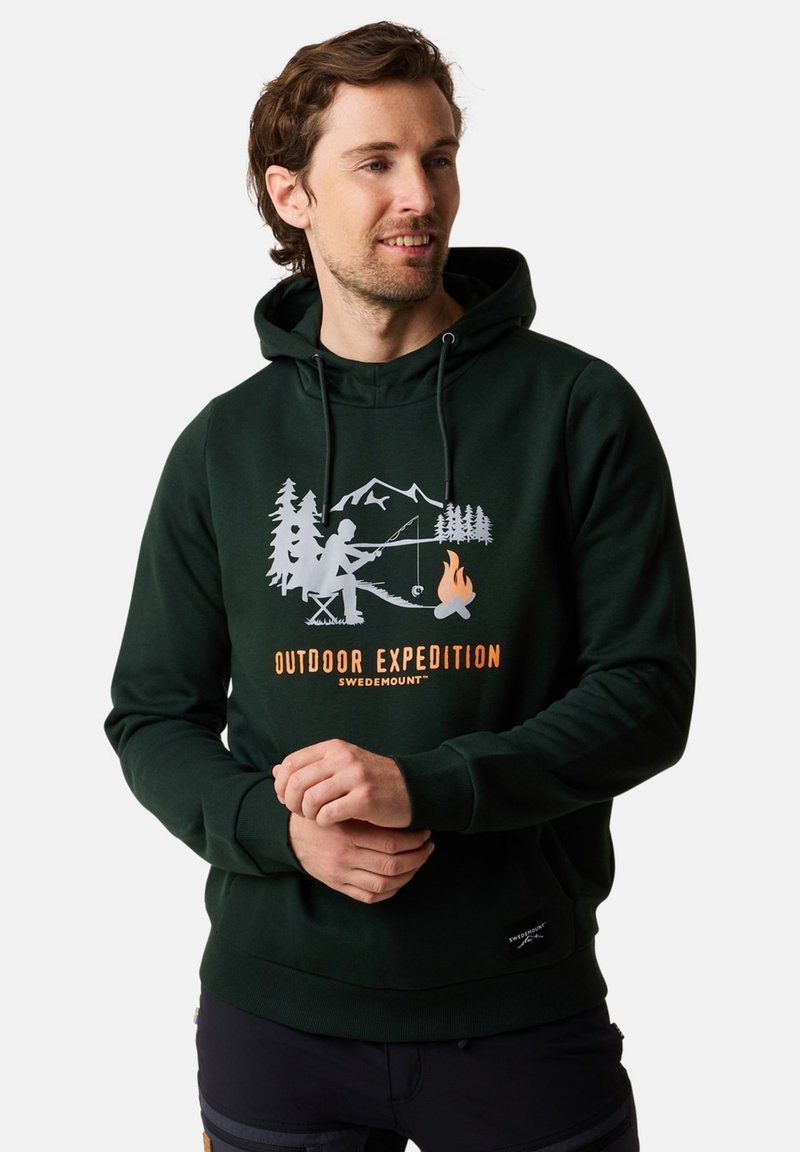 Felpa con cappuccio verde scuro con una grafica frontale che rappresenta scene di campeggio e pesca, con testo bianco e arancione. Materiale morbido in cotone, cappuccio con cordino.