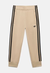 Bež trenirka hlače s crnim bočnim prugama i malim logotipom na lijevoj nozi. Imaju elastični pojas i rebraste manžete na gležnjevima.