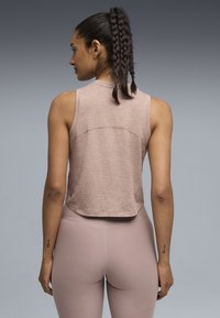 Ανοιχτό ροζ αμάνικη κορυφή cropped αθλητική με υφασμάτινη υφή και στρογγυλεμένο τελείωμα, συνδυασμένη με εφαρμοστά κολάν στο ίδιο χρώμα.
