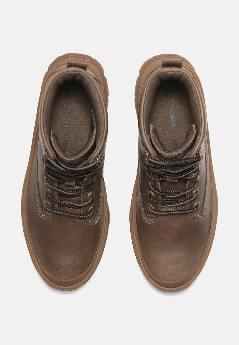 Stivali di pelle marrone con una finitura texturizzata, colletto imbottito, occhielli in metallo e lacci scuri. Suola in gomma con un bordo leggermente rialzato.