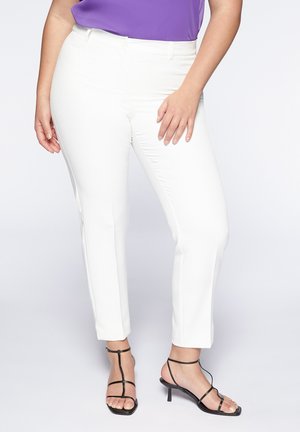 Un pantalon blanc à jambes droites avec une fermeture à bouton et des passants de ceinture, associé à des escarpins à lanières noirs, sur un fond clair.