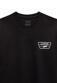 T-shirt en coton noir avec une coupe classique, col rond côtelé et un graphique logo Vans blanc sur la poitrine. Texture lisse, design minimal.