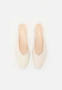 Bež slingback čevlji s koničastim nosom, gladko usnjeno zgornjo plastjo in minimalističnim dizajnom; imajo nizko peto in mehko notranje podlogo.