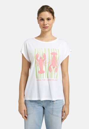Frau trägt ein weißes T-Shirt mit zwei rosa Hummern und grünem Seetang, darunter steht der Text „Living the lobster life“, kombiniert mit hellblauen Jeans.