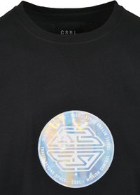 Crni pamučni majica s velikim iridescentnim kružnim grafičkim uzorkom i bijelim tekstom te stiliziranim logotipom u središtu područja prsa.