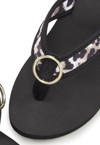 Zwarte flip-flop met een textuur in de zool, voorzien van een luipaardprint band en een gouden cirkelvormige accent bij de verbinding tussen de teen en de band.