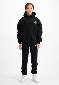 Zwart hoodie- en sweatpants-set met een voorzak, featuring groene grafische accenten. Gestructureerde stof met een relaxte pasvorm en ribgebreide boorden.