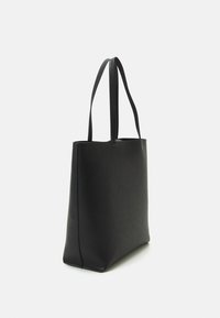 Grand sac fourre-tout en cuir noir avec deux longues poignées, texture lisse et base rectangulaire sur fond blanc.