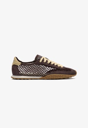 Zapatilla marrón con cordones beige y lengüeta en el talón, con diseño de malla y suela de goma texturizada, mostrada de lado sobre un fondo blanco.