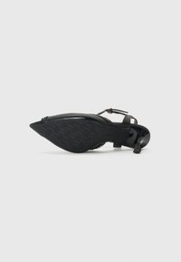 Zwarte lakleren schoen met een puntige neus en enkelbandje. Voorzien van een gestructureerde zool met een houndstoothpatroon en een slanke hak.
