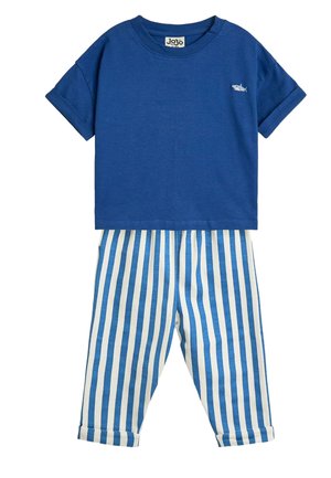 Krótka niebieska koszulka z małym haftem rekina w połączeniu z białymi i niebieskimi pionowo paskowanymi spodniami z podwiniętymi mankietami.