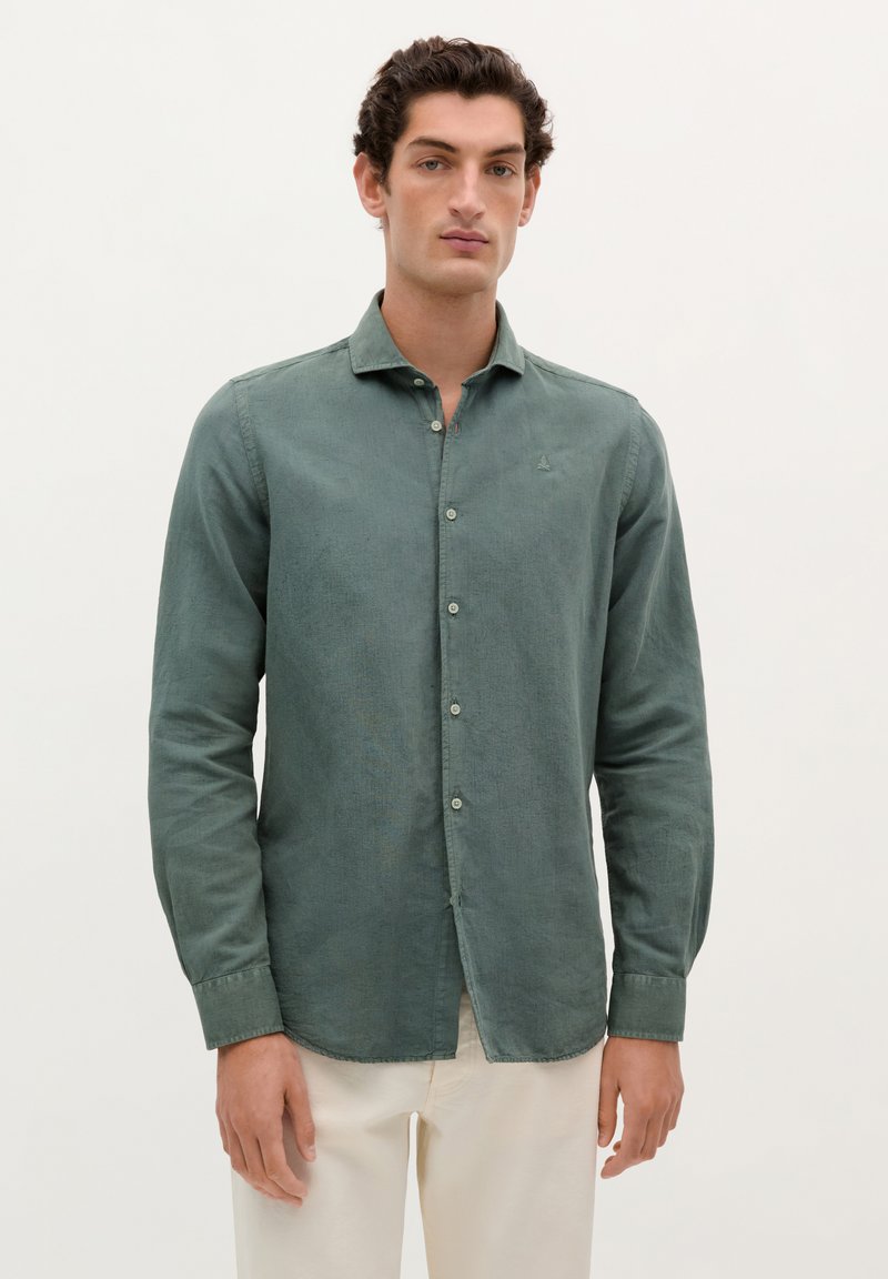 Camisa verde de manga larga hecha de tela texturizada, con un cuello abotonado y botones en la parte frontal, y un sutil logo en el pecho.