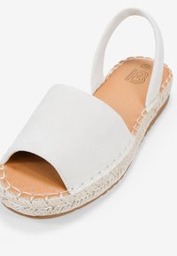 Sandal espadrille bianco con punta aperta, realizzato in tessuto morbido. Presenta una suola in juta intrecciata e una punta arrotondata. Design semplice.