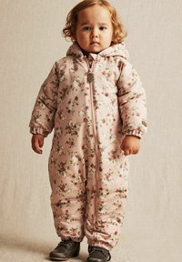 Roze bloemen geïsoleerde sneeuwpak met een ritssluiting aan de voorkant, lange mouwen en elastische manchetten, gecombineerd met zwarte laarzen. Bevat een capuchon en bloemenpatroon.