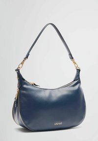 Dunkelblaue Lederhandtasche mit geschwungener Form, goldfarbigen Hardware-Akzenten, Reißverschluss oben und geprägtem Logo auf der Vorderseite.