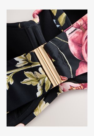 Bloemenbralet met zwarte stof met roze en groene print, detail met gouden gesp en zachte textuur met gestikte randen.