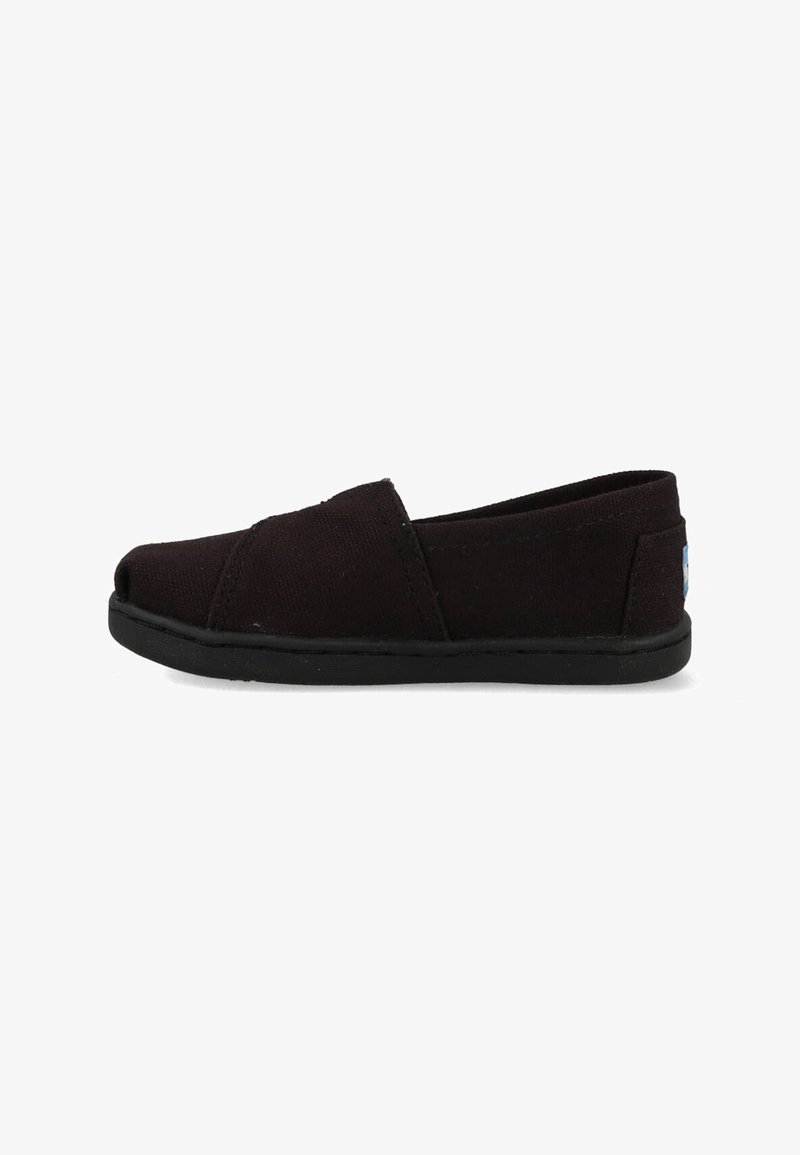 Chaussure noire en toile à enfiler avec semelle plate et bout arrondi, vue de côté sur fond blanc.