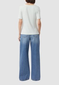 Koszulka krótki rękaw w paski z miękkiego materiału, z jasnoniebieskimi i białymi poziomymi paskami. Połączona z szerokimi, jasnoniebieskimi dżinsami z kieszeniami.