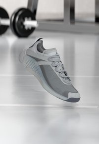 Αθλητικό παπούτσι ανοιχτού γκρι με διάτρητο πάνω μέρος, επενδεδυμένη γλώσσα και ελαστική σόλα. Διαθέτει διακριτικές σκουρότερες γκρι λεπτομέρειες και λεπτό και αεροδυναμικό σχεδιασμό.