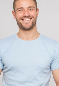 T-shirt en coton bleu clair à manches courtes et à col rond. Présente un logo subtil en relief sur la poitrine. Texture lisse.