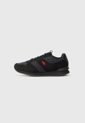 Zwarte en grijze atletiekschoenen van suede en textiel, met een rood logo, een gestructureeerde zool en een klassieke hardloopschoen-silhouet.