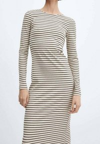 Pitkähihaisen, istuvan mekko beige ribbitetusta kankaasta, jossa on mustia pystysuoria raitoja. Mekossa on pyöreä kaula-aukko ja sileä rakenne.