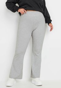 Grå vida träningbyxor i mjukt bomullsblandat tyg med en slät yta, med hög midja och sidoflikar vid fållen.