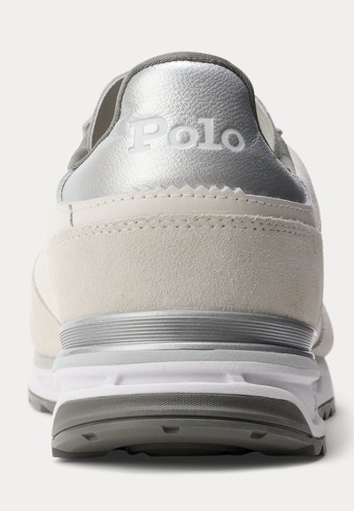 Widok z tyłu beżowo-srebrnych sneakersów z "Polo" wytłoczonym na srebrnej zakładce na pięcie, białą śródpodeszwą oraz szarą podeszwą zewnętrzną.