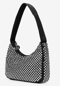Bolso negro bandolera con forma curva, cubierto de tachuelas plateadas. Presenta un cierre con cremallera y una correa de tela para un fácil transporte.