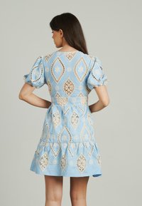 Hellblaues Kleid mit Puffärmeln, aufwendigen Spitzenverzierungen in einem Diamantmuster, gestuftem Rock und taillierter Passform.