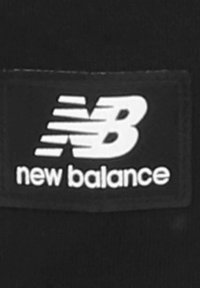 Etiqueta negra con texto blanco; presenta el logotipo "NB" con líneas de velocidad sobre las palabras "new balance" en una fuente moderna.