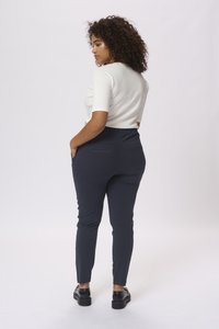 Pantaloni fitted blu navy con una cintura elasticizzata, due tasche posteriori e una texture di tessuto liscia. Modello mostrato da dietro.