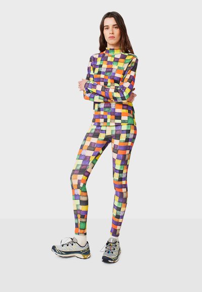 Colorful, patterned activewear set: long-sleeve top and leggings featuring a grid design in purple, orange, green, and yellow. Textured fabric.