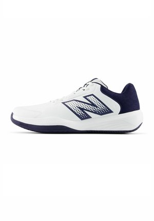 Chaussure de sport blanche avec semelle, talon et grand logo « N » décoré en bleu foncé sur le côté, affichée en vue de profil latéral.