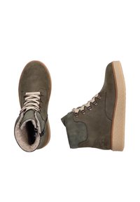 Bottes en daim vert olive avec des lacets beiges, semelles en caoutchouc beige et doublure douce ; elles possèdent une fermeture éclair sur le côté et des coutures décoratives.