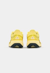 Zapatillas de running Gore-Tex amarillas con un upper de malla texturizada, suela acolchada y plantilla de goma negra con un intrincado patrón de tacos.