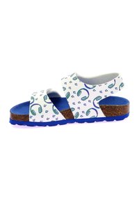 Sandalias blancas con un patrón de auriculares verdes y azules repetidos, suela de corcho y fondo de goma azul. Cuentan con correas ajustables para un mejor ajuste.