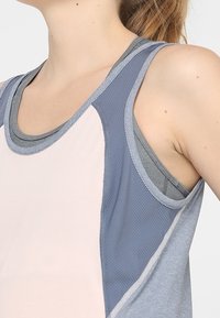 Lekki sportowy top na ramiączkach, z różowymi, szarymi i jasnoniebieskimi panelami; siateczkowa tekstura; kontrastowe przeszycia; design z plecakiem dla lepszej wentylacji.